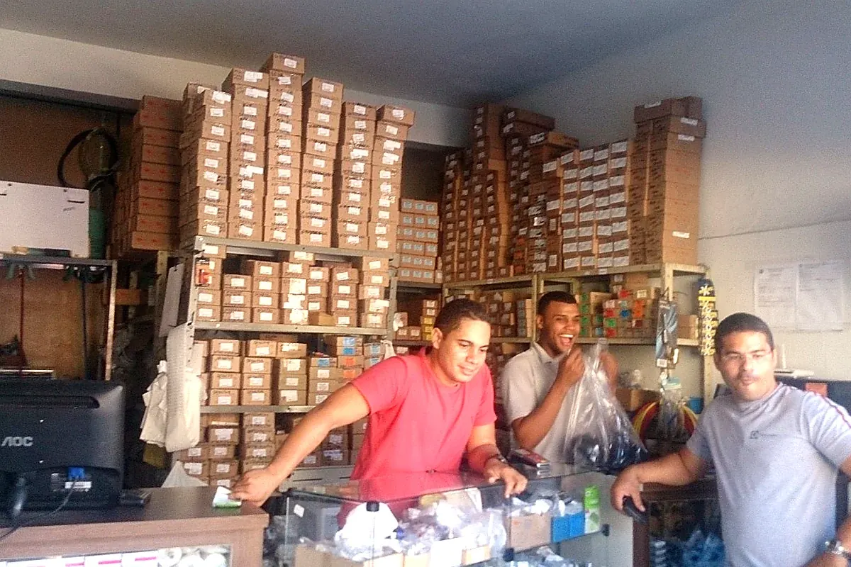Equipe da JR Refrigeração no balcão com estoque de peças ao fundo